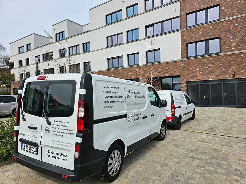 Fahrzeuge von Kaster’s Gebäudeservice vor einer Wohnanlage